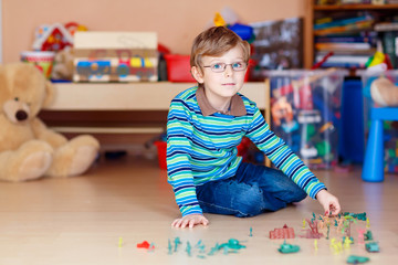 Kid boy playing with toy soldiers indoors at nursery