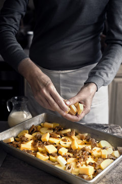 Adding cheese in the baking tray with ingredients for tartiflette