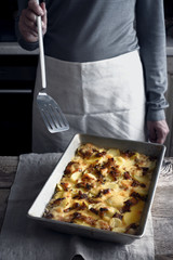 Tartiflette in the baking tray on the wooden table vertical