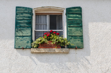 Window in an old house decorated with flower pots and flowers