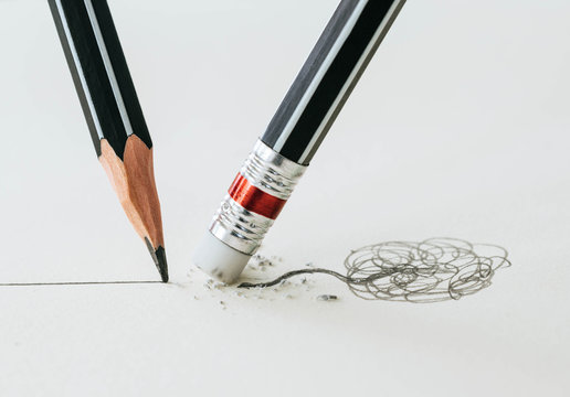 Close up of a pencil eraser removing a crooked line and the clos