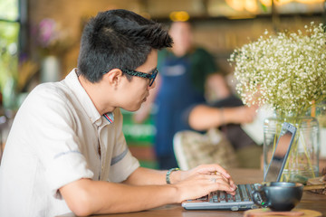Young handsome man using laptop computer in cafe
