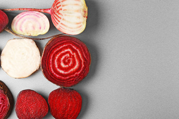 Fresh young sliced beets and carrots on grey background