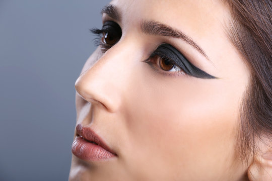 Portrait of young attractive woman with beautiful eye makeup on grey background