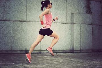 Fototapeta premium young fitness sport woman running against wall on city