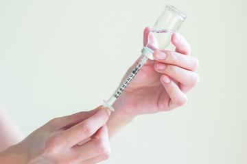 Nurse is  drawing  solution into syringe from vial for preparing