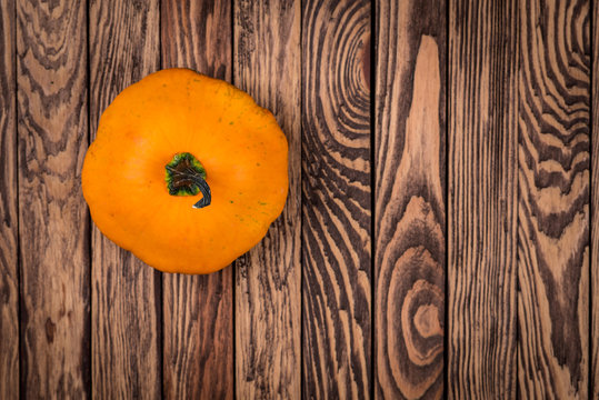 One autumn pumpkin on wooden background, top view image. Autumn background, wallpaper, poster.