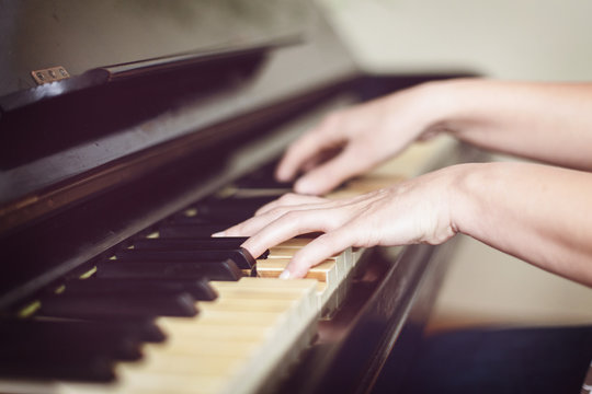 Close up of two hands playing piano, shallow focus.