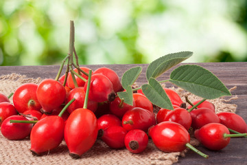 fresh rose hips on a dark board with sackcloth and  blurred background