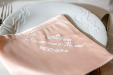 Pink serviette with wedding couple names lies on a dinner plate