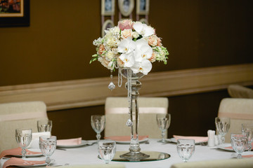 Festive dinner table with glassware and a high vase with rich bo