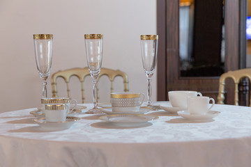 Different kinds of glassware and cups stand on a round dinner ta