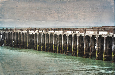 Historic old wooden Sumpter Wharf at Oamaru Harbour, New Zealand. Vintage, grunge textured image. Roosting site for colony of shags (waterbirds).