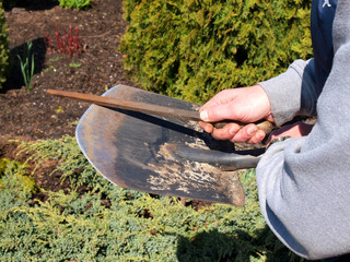 Sharpening garden shovel blade with file outdoor close up