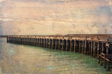 Historic old wooden Sumpter Wharf at Oamaru Harbour, New Zealand. Vintage, grunge textured image. Roosting site for colony of shags (waterbirds).