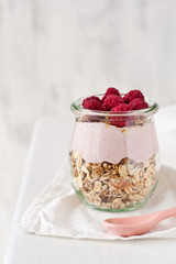 Müsli, Yoghurt und Himbeeren im Glas zum Frühstück
