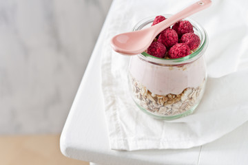 Müsli, Yoghurt und Himbeeren im Glas zum Frühstück
