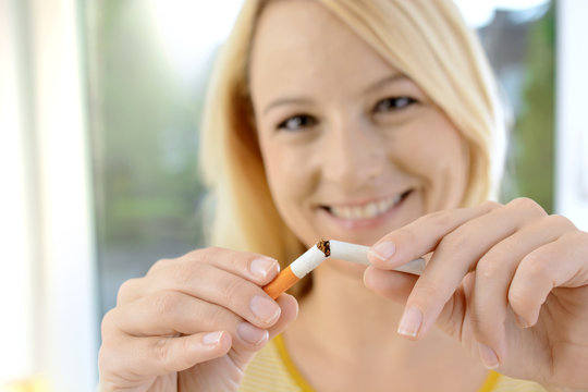 Frau bricht Zigarette durch und will als Nichtraucher mit dem Rauchen aufhören