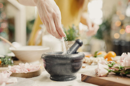A hand adding ingredients to a pestle and mortar on a kitchen counter. 