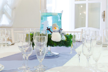 A little snowman stands in the middle of a restaurant table