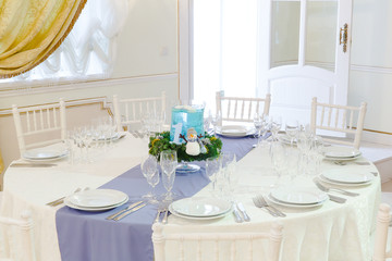 Round white table served for a festive dinner and decorated in w