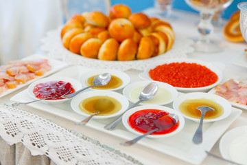 Different kinds of sauces lie in round plated on a square dish
