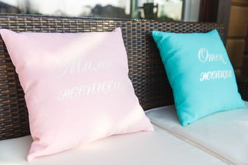 Pink and blue pillows with lettering lie on the brown sofa