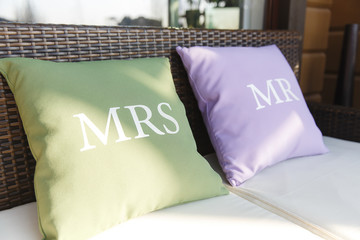 Lettering Mr and Mrs on little pastel pillows which lie on the s