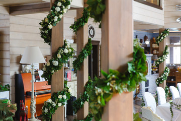 Flower garlands made of roses and greenery cover wooden pillars