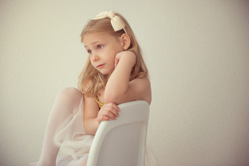 Pretty seriously ballet girl in white tutu sitting on chair - obrazy, fototapety, plakaty