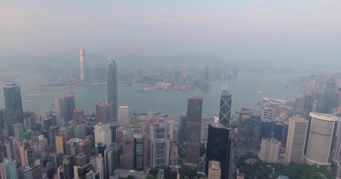 Beautiful aerial shot of many high  skyscrapers covered with sunset fog or haze in Hong Kong, China. Top view of Victoria Harbour from Victoria Peak at sunset. City skyline.