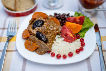 Beef stew with carrot and dried plum, topping with rice, beans and tomatoes. Served on a white...