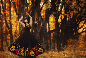Portrait of a beautiful girl in a national dress in autumn in th