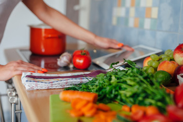 Young woman is preparing a meal while using tablet pc.