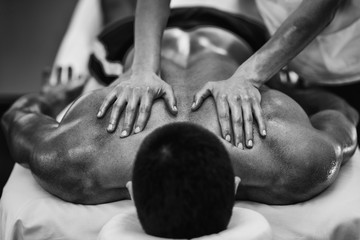 Sports massage. Massaging shoulders. Black and white