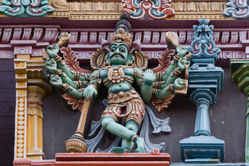 Fototapeta na wymiar Madurai, India - October 19, 2013: Closeup of eight-armed Dwarapalaka on the facade of the North Gopuram at Meenakshi Temple.
