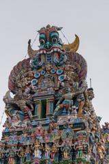 Madurai, India - October 19, 2013: Closeup of the short side of West Gopuram at Meenakshi Temple. Abundance of pastel colored statues. Monster, dwarapalakas, bulls, gods.