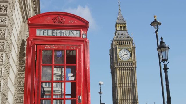 Traditional red telephone booth. Big Ben and street lights against blue sky. Famous place and tourist destination landmark in London, England, UK, Europe.