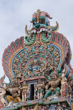 Madurai, India - October 19, 2013: Closeup of the top of South Gopuram at Meenakshi Temple. Lord Vishnu as Narasimha surrounded by servants and his two wives on his knees.