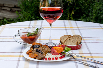 Beef stew with carrot and dried plum, topping with rice, beans and tomatoes. Served on a white plate with crusty bread, home made sauce and glass of red wine.