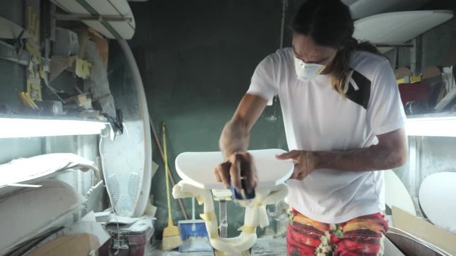 Surfboard making, Shaper is shaving and cleaning a line on a surfboard