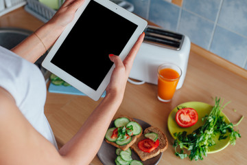 Young woman is preparing a meal while using tablet pc.