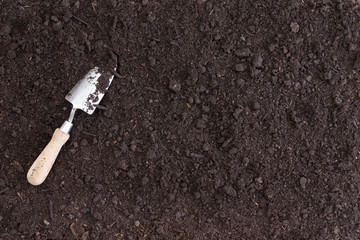 A single white spade lies in rich black soil