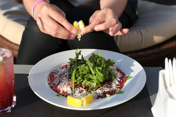 Squeezing juice of lemon into meat carpaccio.