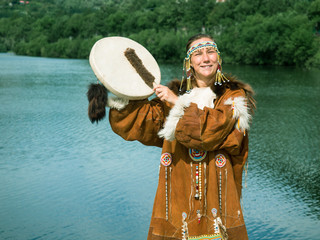 Adult woman in traditional Koryak dress holding a tambourine and playing on it on the Kamchatka...