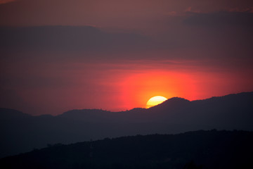 Piece of sun behind the mountains at sunset