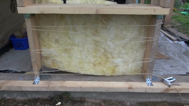 Builder preparing to insulate new house wall with blanket insulation with help of strings