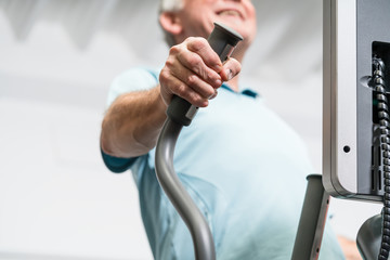 Älterer Mann trainiert am Crosstrainer im Fitnessstudio