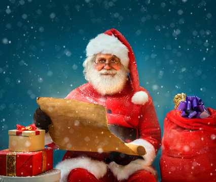 Santa Claus holding vintage paper and reads long list of gifts for children. Merry Christmas & New Year's Eve concept.