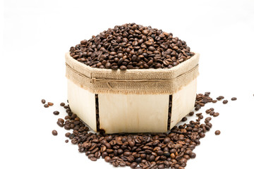 a lot of roasted coffee beans in a box made of natural materials on a white background